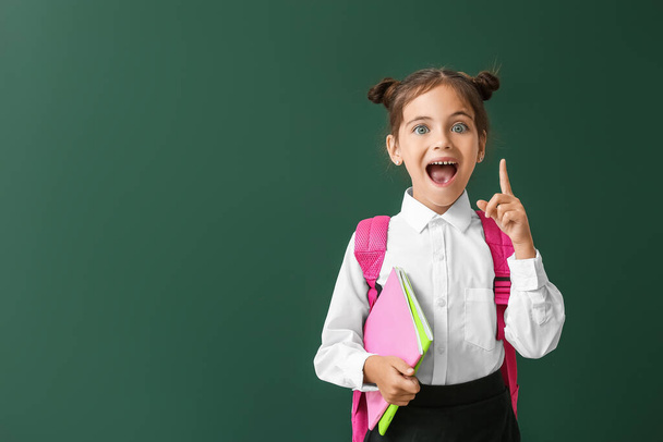 Malá školačka se zvednutým ukazováčkem na barevném pozadí - Fotografie, Obrázek