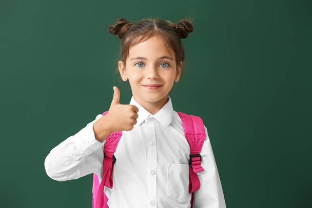Little schoolgirl showing thumb-up on color background - Foto, afbeelding