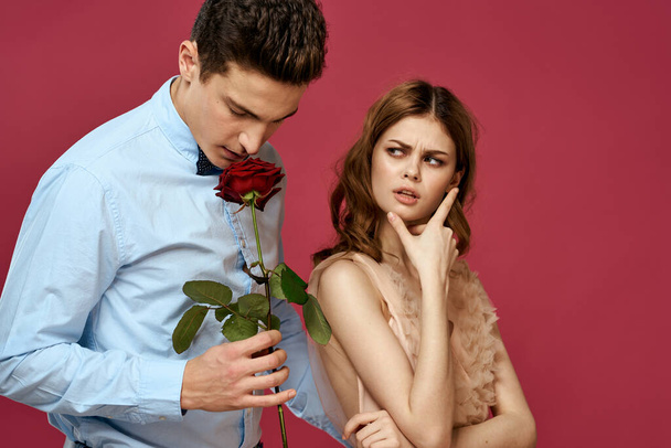 Εραστές άνθρωποι με τριαντάφυλλο στα χέρια σε ροζ απομονωμένη φόντο αγκαλιάζουν τα συναισθήματα ευτυχία ρομαντική συναισθήματα - Φωτογραφία, εικόνα