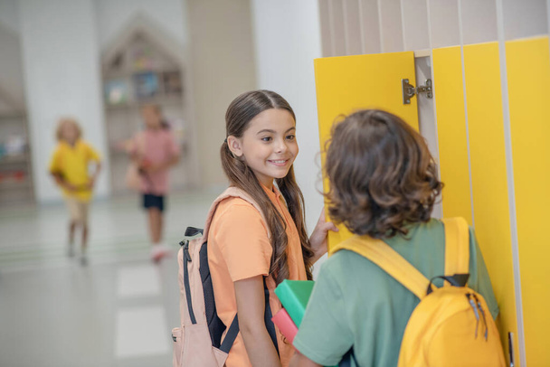 Dark-haired girl talking to her classmate and smiling - Photo, image