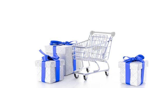 ギフトボックス分離。白い背景に隔離されたクリスマスや誕生日のギフトボックスとスーパーマーケットのためのトロリーカート。販売、割引、ショッピングの概念。消費者社会の動向 - 写真・画像