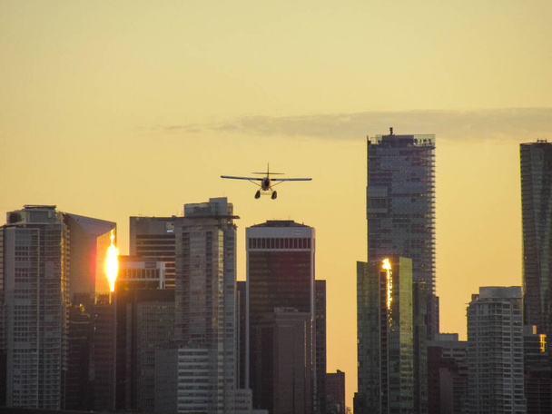 Seaplane προσγείωση με ουρανοξύστες Βανκούβερ και όμορφα κίτρινα χρώματα ηλιοβασίλεμα στο παρασκήνιο. - Φωτογραφία, εικόνα