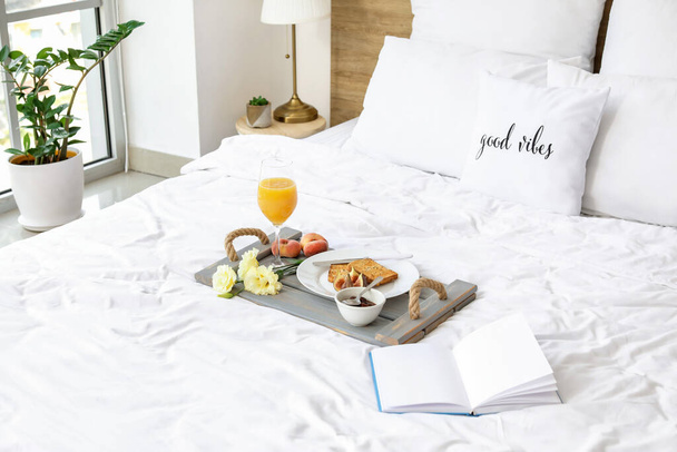 Лоток зі смачним сніданком і книгою на ліжку
 - Фото, зображення