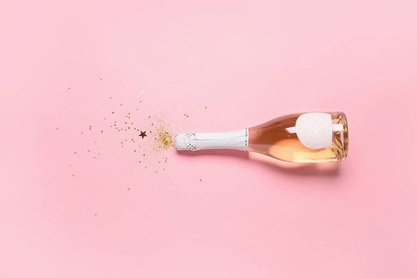 Bottle of champagne and glitters on color background. New Year celebration - Fotografie, Obrázek