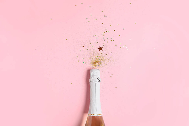 Garrafa de champanhe e brilhos no fundo de cor. Celebração de Ano Novo - Foto, Imagem