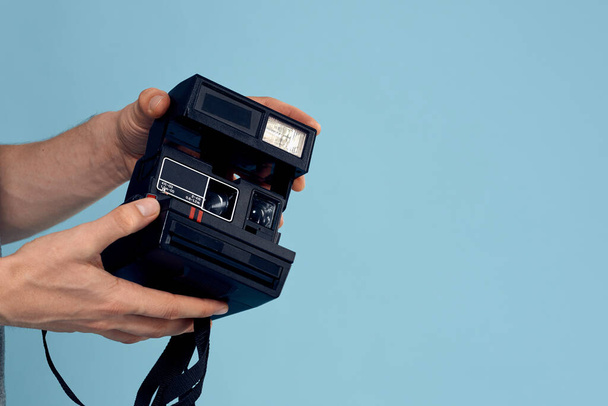 Fotocamera in de handen van een man professionele schieten lens technologie studio apparatuur blauwe achtergrond - Foto, afbeelding