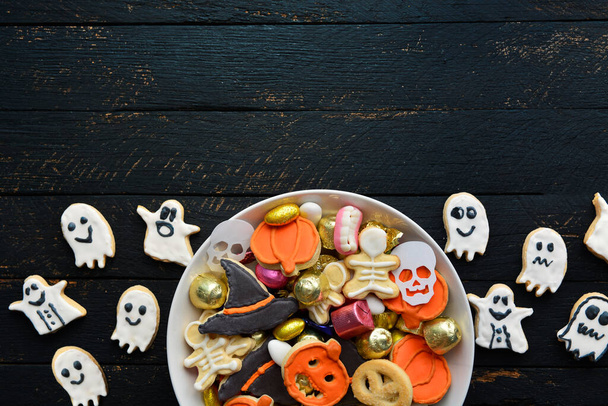 Halloween Jack o Lantern candy bowl with candy and halloween cookies Trick or Treat on black wooden background - Foto, immagini