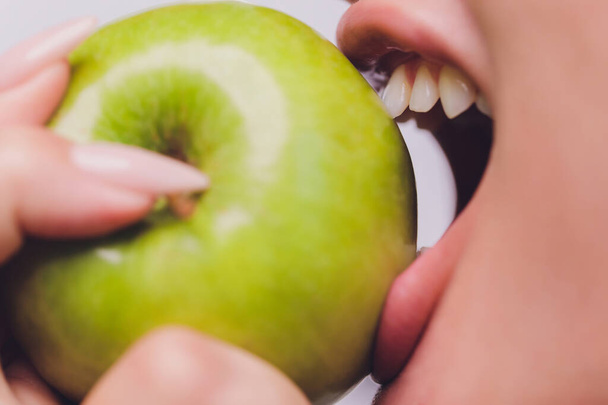 Pretty young woman with beautiful white teeth holding an apple in her hand. - Foto, Bild