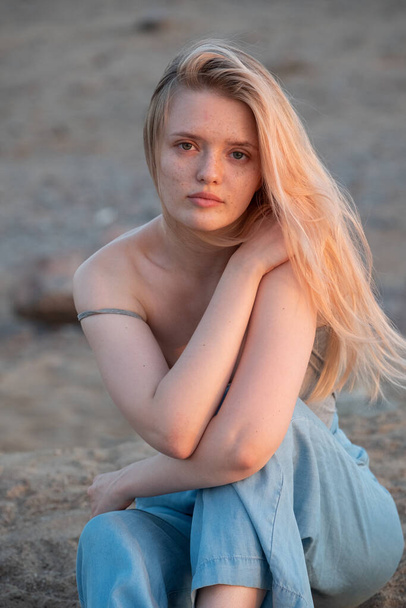 Outdoor fashion portrait of a  young woman with with straight blond hair at sunset - Foto, imagen