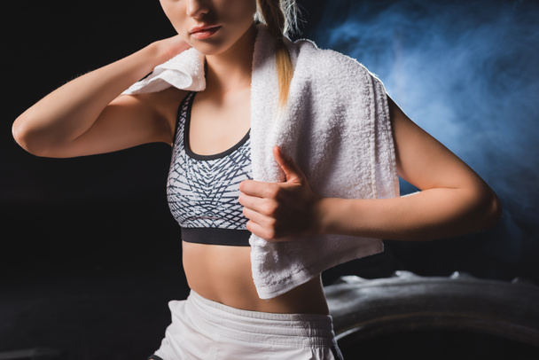 Cropped view of young sportswoman holding towel in sports center with smoke  - Foto, Imagen