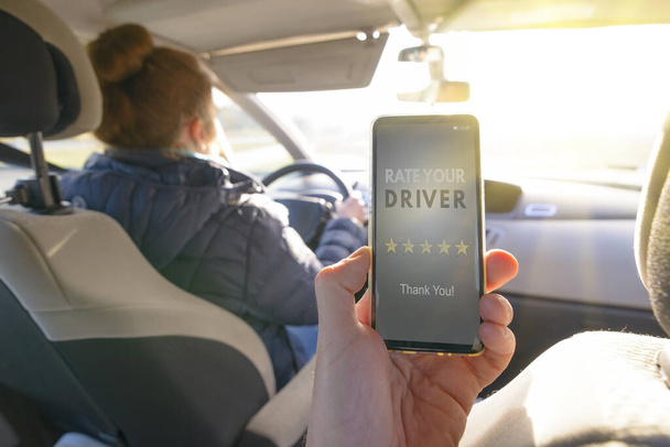 Matkustaja istuu auton takapenkillä ja käyttää älypuhelinsovellusta kuljettajan arvioimiseen. Taksi tai moderni peer to peer ridesSharing käsite - Valokuva, kuva