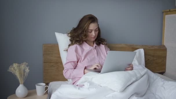 Female with laptop on bed in morning time - Filmati, video