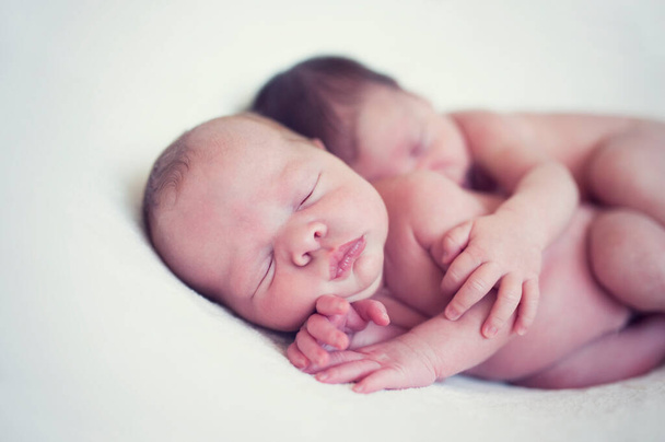 Az újszülött ikrek egy ölelésben alszanak együtt. A babák együtt fekszenek a takarón. Testvéri szeretet születéstől fogva - testvérek, testvérek. Gyermekgondozás - Fotó, kép
