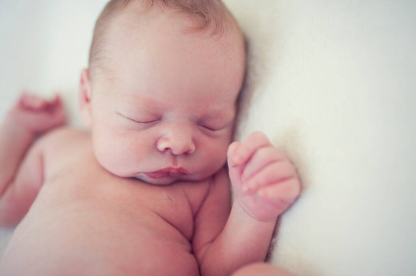 Zufriedenes Baby, das auf einer Decke schläft. Porträt eines Neugeborenen. - Foto, Bild