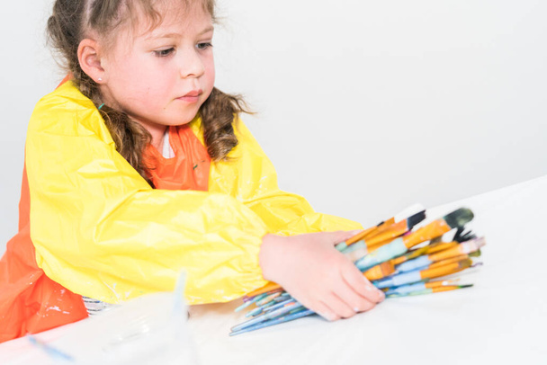 Egy kislány, aki egy művészeti projekten dolgozik akril festékkel a magániskolában.. - Fotó, kép