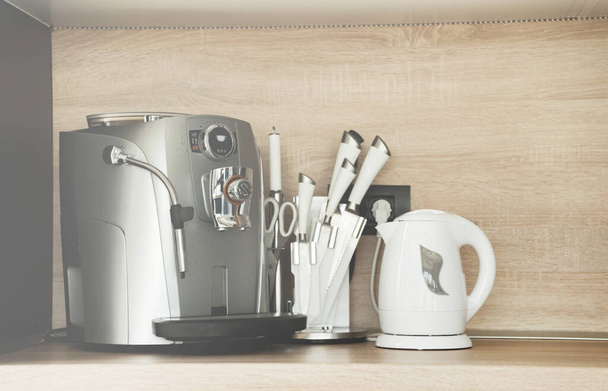 Una cafetera cerca de unos cuchillos y un hervidor de agua en la cocina - Foto, imagen