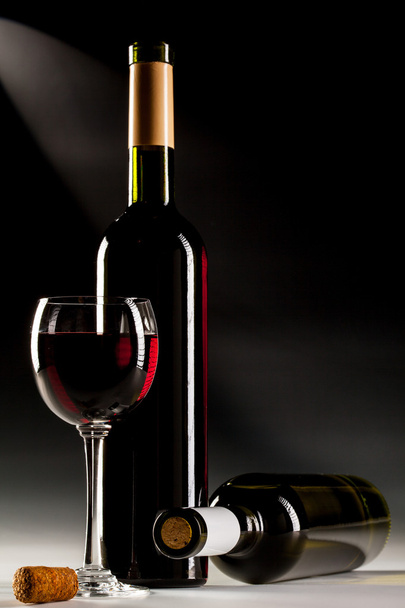 Filled glass of red wine and wine bottles - Foto, immagini