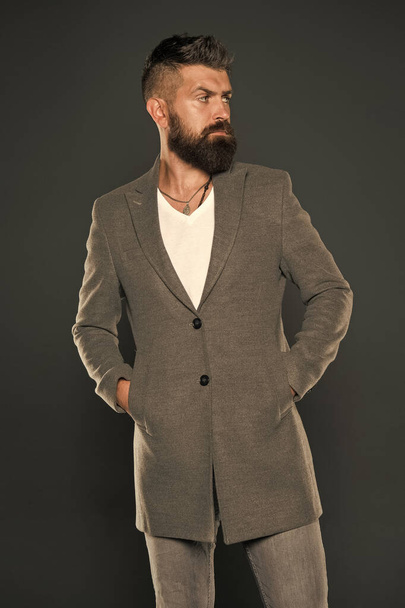 Serious concentrated man. Caucasian man with brutal appearance. Bearded man with moustache and beard on unshaven face in brutal style. Brutal hipster wearing casual outfit. Comfortable simple coat - Fotografie, Obrázek