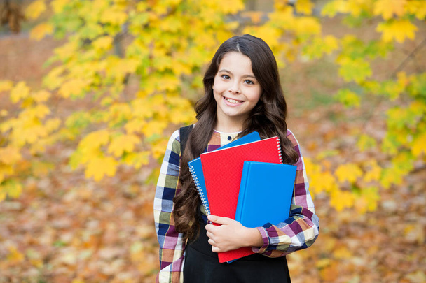 concept of knowledge day. kid in autumn park. happy kid with books in autumn leaves. small girl wear uniform. back to school. modern education. child with notebooks in fall forest - Zdjęcie, obraz