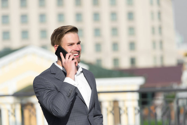 Business communication and new technology. Happy businessman with smartphone on sunny terrace. Man smile in formal suit with mobile phone outdoor. Business lifestyle concept - Foto, immagini