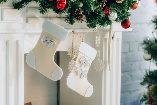 Evde şöminenin yanında Noel çoraplarıyla süslenmiş bir çam dalı. - Fotoğraf, Görsel