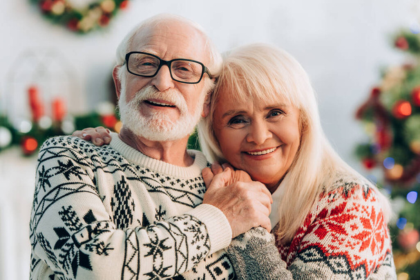 happy senior couple embracing while smiling at camera - Fotografie, Obrázek