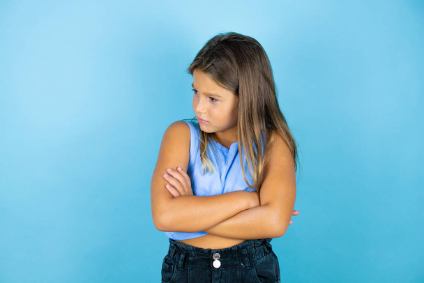 Молодая красивая девочка на изолированном синем фоне думает усталый и скучно со скрещенными руками - Фото, изображение