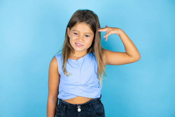 Young beautiful child girl over isolated blue background Shooting and killing oneself pointing hand and fingers to head like gun, suicide gesture. - Photo, Image