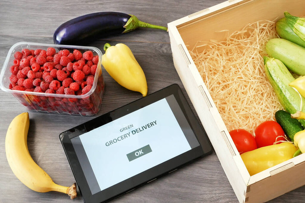Βιολογικά Λαχανικά και φρούτα σε ξύλινο κουτί και tablet pc, σε απευθείας σύνδεση αγορά, πράσινο παντοπωλείο παράδοση στο σπίτι έννοια, να αγοράσουν online  - Φωτογραφία, εικόνα