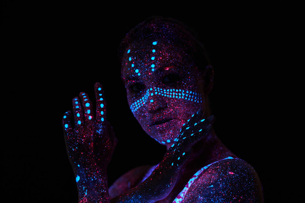 Art woman cosmos in ultraviolet light. Entire body is covered with colored droplets. Girl posing in the dark. Noise, out of focus - Photo, Image