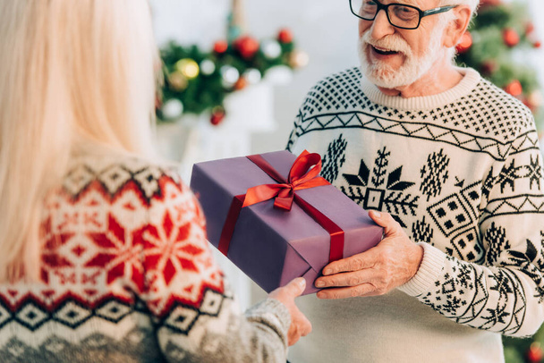 selective focus of senior man presenting gift box to wife - Fotografie, Obrázek