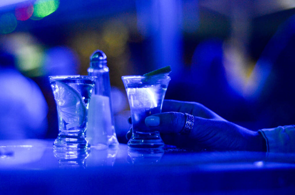 Shot of tequila. Limes, salt and shots on table in nightclub. Glass of alcohol drink in pub. - Photo, Image