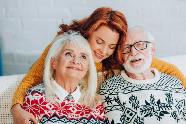 happy daughter embracing smiling senior parents with closed eyes - Foto, immagini