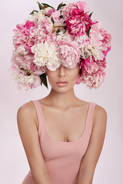 Beautiful woman with pink peony flowers, natural beauty, skin care. Perfect facial features. Girl posing on a light background - Φωτογραφία, εικόνα