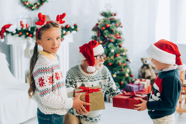 uomo anziano in cappello di Babbo Natale prendere regali da nipoti a Natale - Foto, immagini
