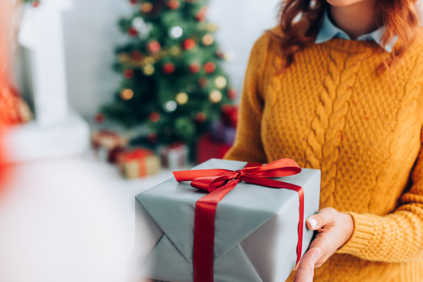 cropped view of woman holding christmas gift box, selective focus - Foto, afbeelding