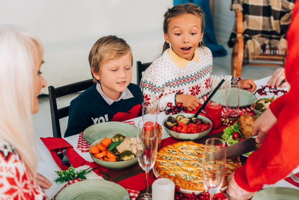 Focus selettivo di bambini eccitati che guardano la torta sul tavolo festivo a casa - Foto, immagini