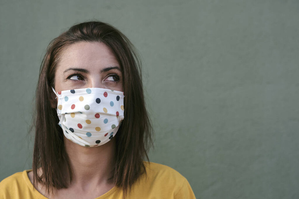 Close-up of young woman with medical mask over green background - Photo, Image