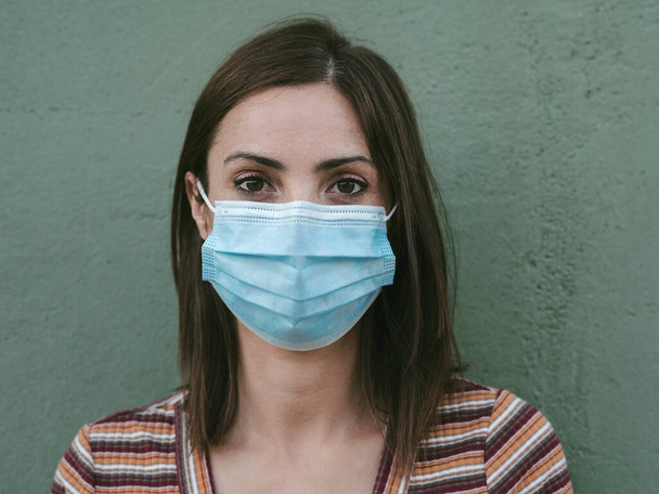 Lähikuva nuori nainen lääketieteellinen naamio yli vihreä tausta - Valokuva, kuva