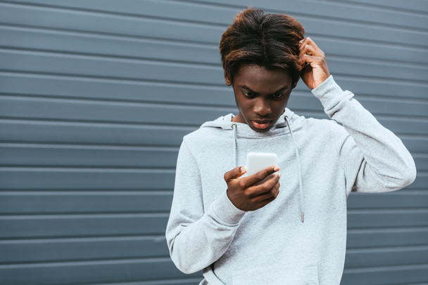 Pensive african american teenager using smartphone outdoors  - Photo, Image