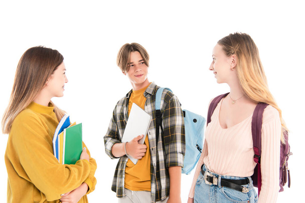 Teenagers with backpacks and notebooks smiling at each other isolated on white - Foto, imagen