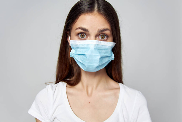 Frau mit medizinischer Maske schnitt Blick auf weißes T-Shirt ab - Foto, Bild