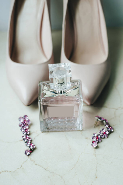 Blush pink bridal shoes and bottle of perfume. Close up and top view.The bride's shoes and perfume. Heeled shoes. Pink fragrance. Bridal accessories. Preparations for the wedding day. - Φωτογραφία, εικόνα