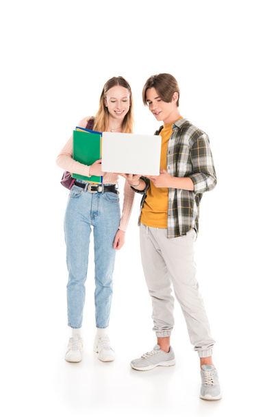 Teen boy holding laptop near friend with notebooks on white background - 写真・画像