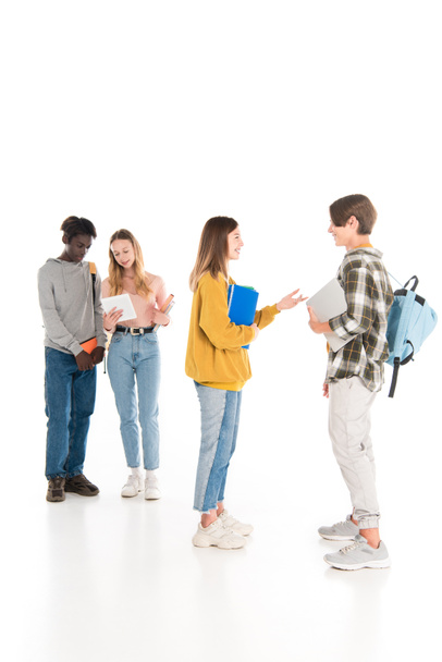 Selective focus of smiling teenagers with notebooks and gadgets talking on white background - Photo, Image