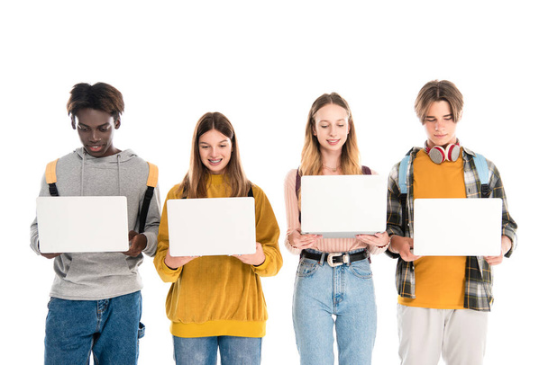 Adolescentes multiculturales positivos sosteniendo computadoras portátiles aisladas en blanco - Foto, Imagen