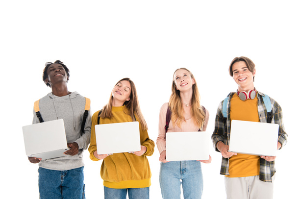Positive multicultural teenagers with laptops and backpacks isolated on white - Φωτογραφία, εικόνα
