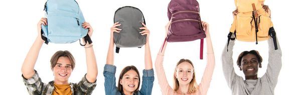 Панорамный снимок улыбающихся мультиэтнических подростков с рюкзаками, изолированными на белом - Фото, изображение
