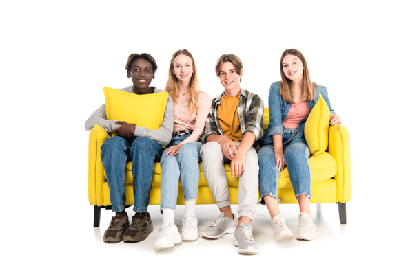 Multiethnic teenagers smiling at camera while sitting on couch on white background - Foto, Imagem