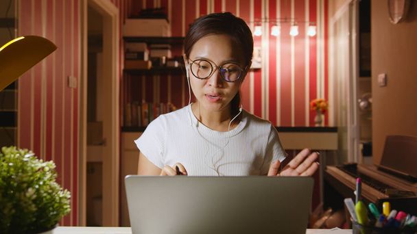 Азиатская деловая женщина работает из дома в ночное время сверхурочно, видео-конференция или виртуальная встреча на ноутбуке - Фото, изображение